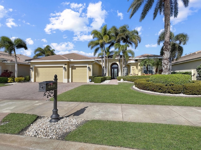 view of front facade with a garage, decorative driveway, a front yard, and stucco siding