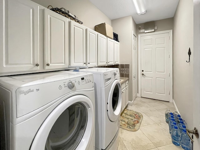 clothes washing area with light tile patterned floors, cabinet space, baseboards, and separate washer and dryer