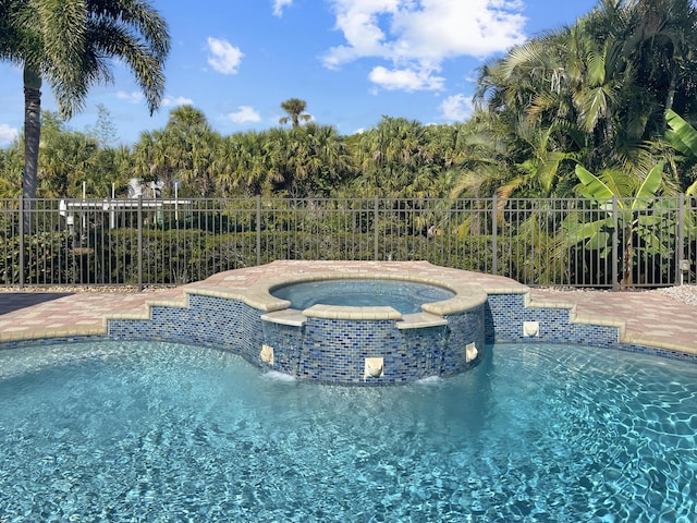 view of swimming pool with fence and a pool with connected hot tub