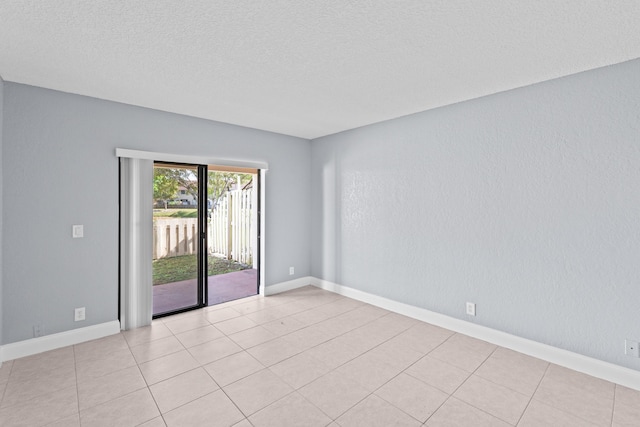 empty room featuring a textured wall, a textured ceiling, and baseboards