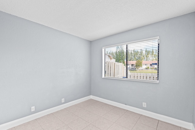 spare room featuring baseboards and a textured ceiling