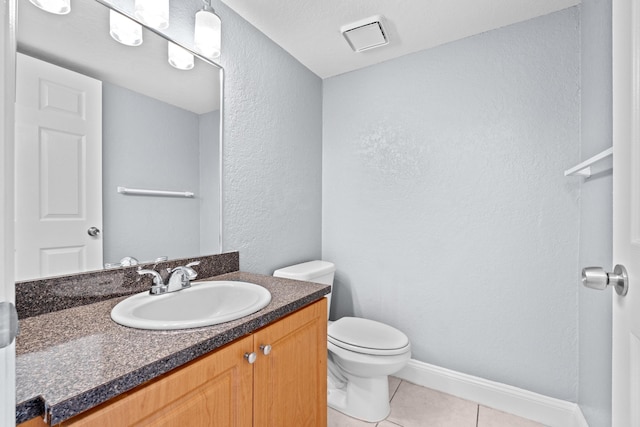 half bath featuring a textured wall, toilet, vanity, tile patterned flooring, and baseboards