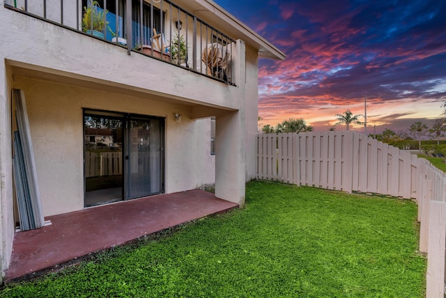 yard at dusk featuring a balcony and fence