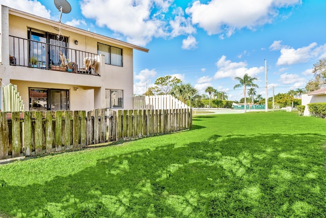 view of yard featuring fence and a balcony