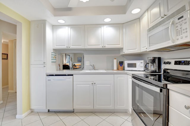 kitchen with light tile patterned floors, white appliances, a sink, white cabinets, and light countertops