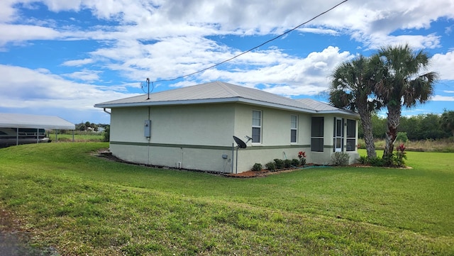 view of side of property with metal roof, a lawn, and stucco siding