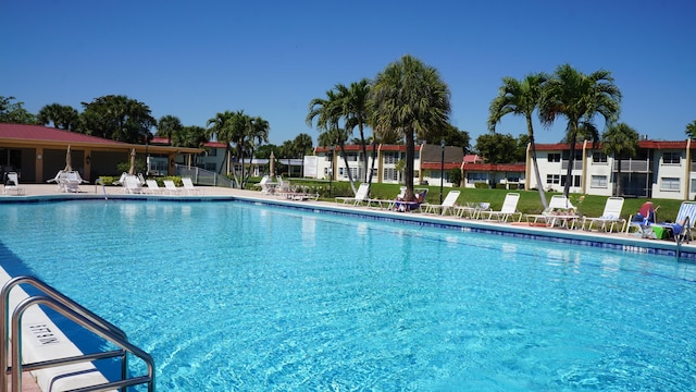 community pool featuring a patio, a lawn, and fence