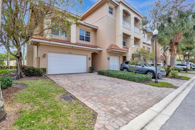 view of front of home featuring stucco siding, decorative driveway, and a tiled roof