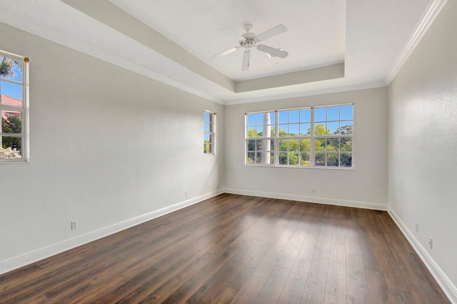 spare room featuring dark wood-type flooring, a tray ceiling, ceiling fan, and baseboards