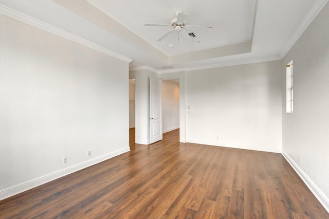 unfurnished room featuring baseboards, a raised ceiling, a ceiling fan, ornamental molding, and dark wood-style flooring