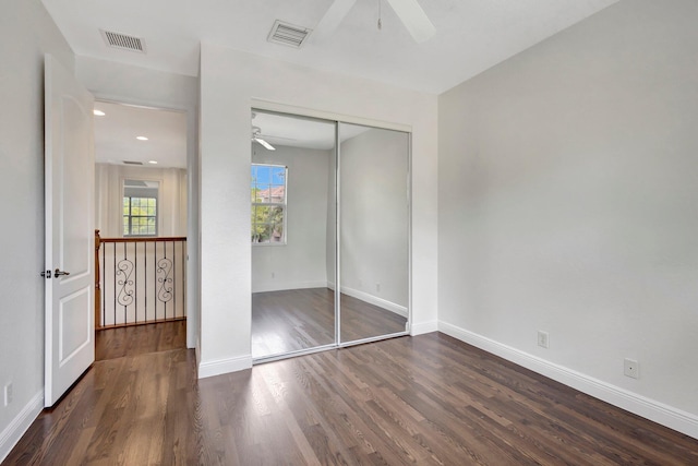 unfurnished bedroom with a closet, wood finished floors, visible vents, and baseboards