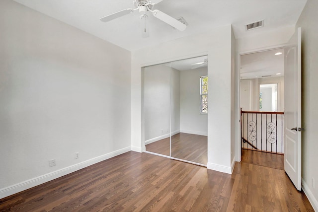 unfurnished bedroom with a closet, visible vents, baseboards, and wood finished floors