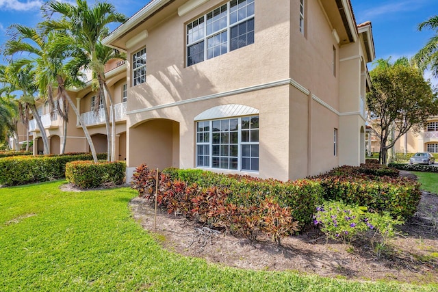 view of side of home featuring a lawn and stucco siding