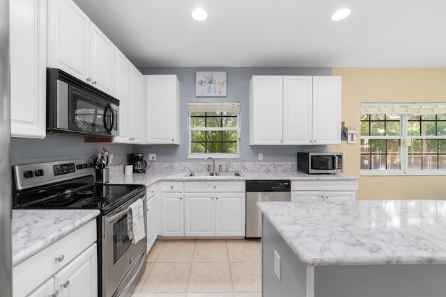 kitchen with stainless steel appliances, white cabinetry, a sink, and light tile patterned flooring