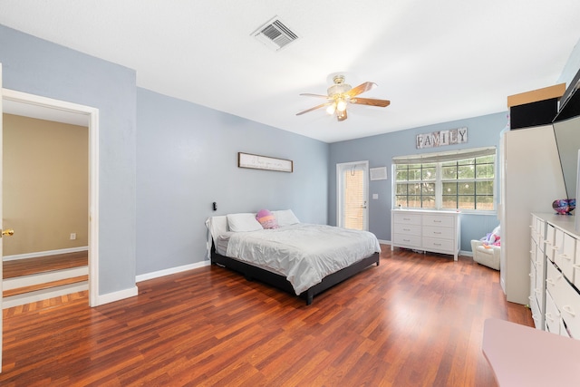 bedroom with a ceiling fan, visible vents, baseboards, and wood finished floors