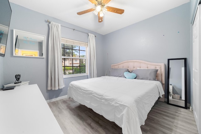 bedroom featuring wood finished floors, a ceiling fan, and baseboards