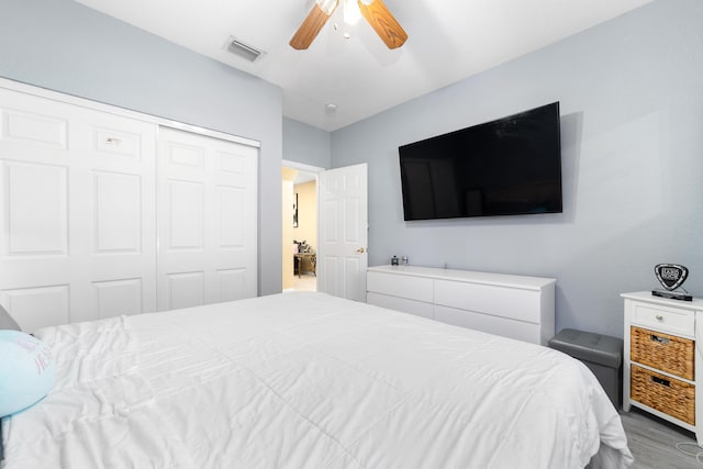 bedroom with a closet, visible vents, ceiling fan, and wood finished floors