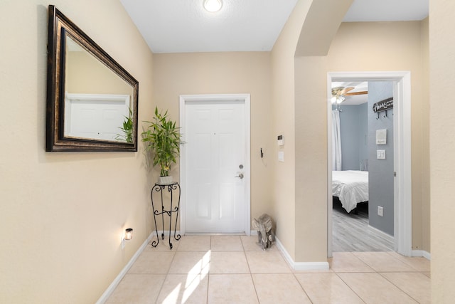entryway featuring arched walkways, baseboards, and light tile patterned floors