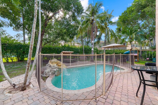 view of swimming pool with a patio area, fence, a fenced in pool, and playground community