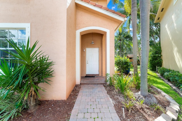 property entrance with a tile roof and stucco siding