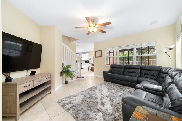 living room with light tile patterned floors, stairway, a ceiling fan, and baseboards