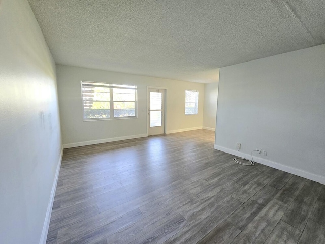 spare room featuring dark wood-style floors, a textured ceiling, and baseboards