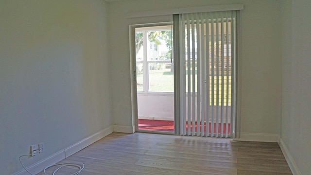 empty room with baseboards, a wealth of natural light, and wood finished floors