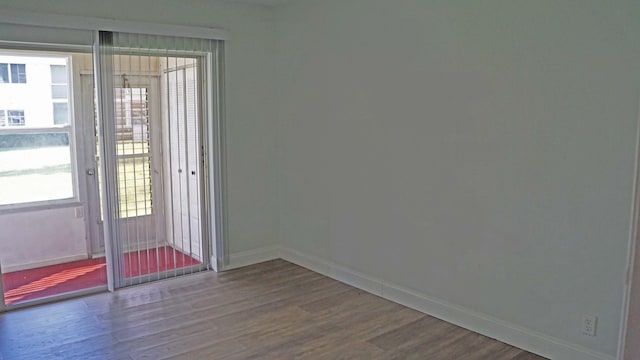 spare room with a healthy amount of sunlight, baseboards, and wood finished floors