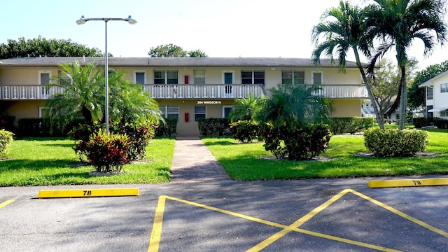 view of front of house featuring uncovered parking, a front lawn, and stucco siding