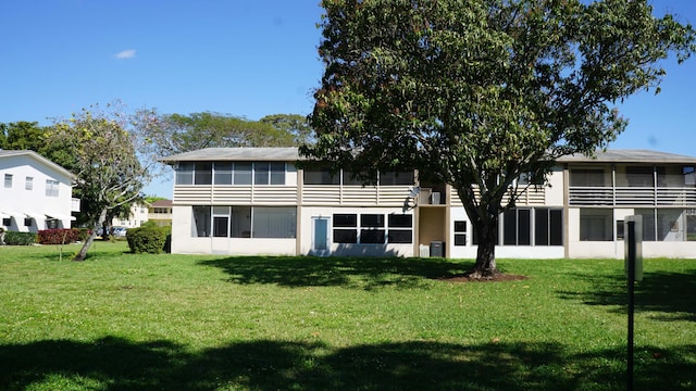 rear view of house with a sunroom and a lawn