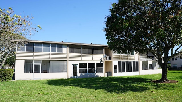 rear view of house featuring a yard, central AC unit, and a sunroom