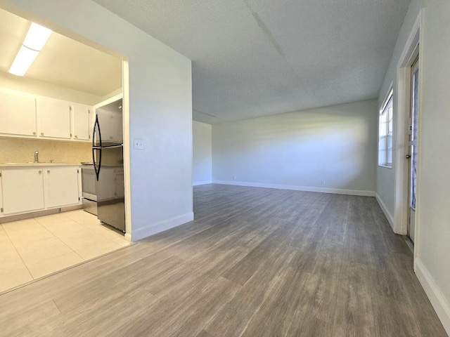 interior space featuring light wood-type flooring, a sink, and baseboards