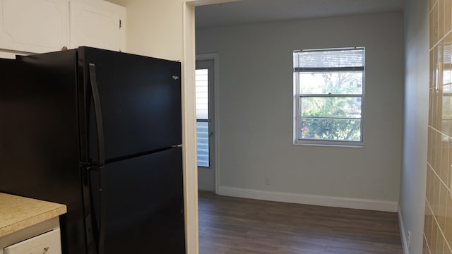 kitchen with baseboards, light countertops, freestanding refrigerator, and white cabinets