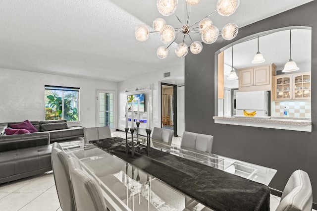 dining area with a chandelier, a textured ceiling, light tile patterned flooring, and visible vents