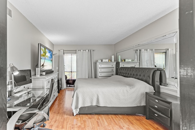 bedroom featuring a textured ceiling, visible vents, and light wood-style floors