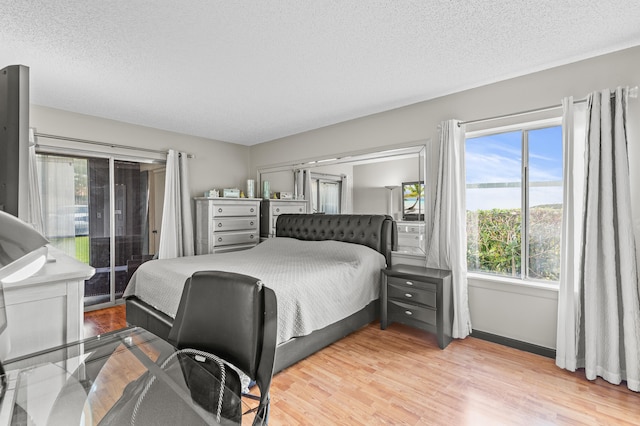 bedroom with a textured ceiling, access to outside, light wood-style flooring, and baseboards