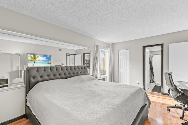 bedroom featuring ensuite bath, a textured ceiling, and wood finished floors