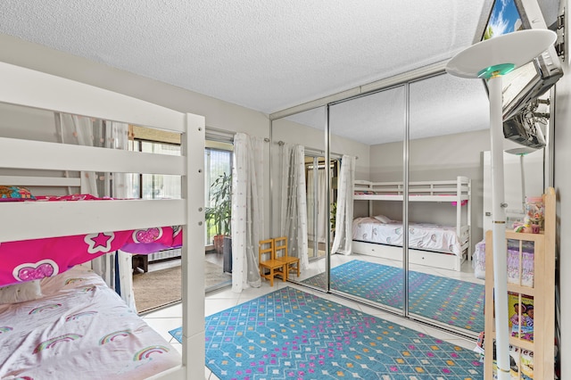 tiled bedroom featuring a textured ceiling, a baseboard heating unit, and a closet