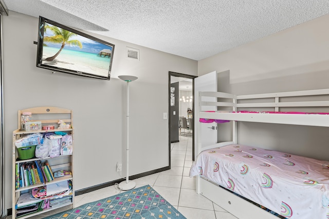 bedroom featuring baseboards, tile patterned flooring, visible vents, and a textured ceiling