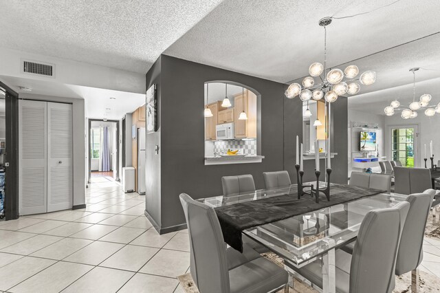 dining space with a chandelier, visible vents, plenty of natural light, and light tile patterned floors