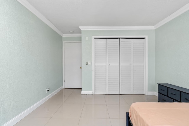 bedroom featuring light tile patterned floors, a textured wall, ornamental molding, and baseboards