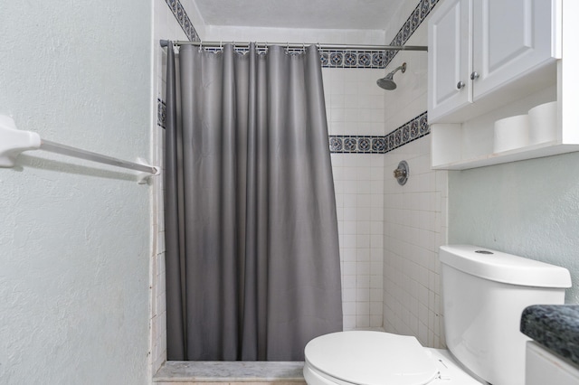 bathroom featuring a textured wall, a tile shower, and toilet