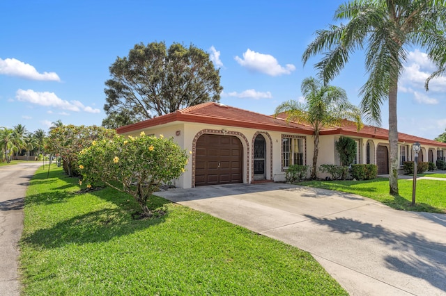 mediterranean / spanish house featuring an attached garage, concrete driveway, a front yard, and stucco siding