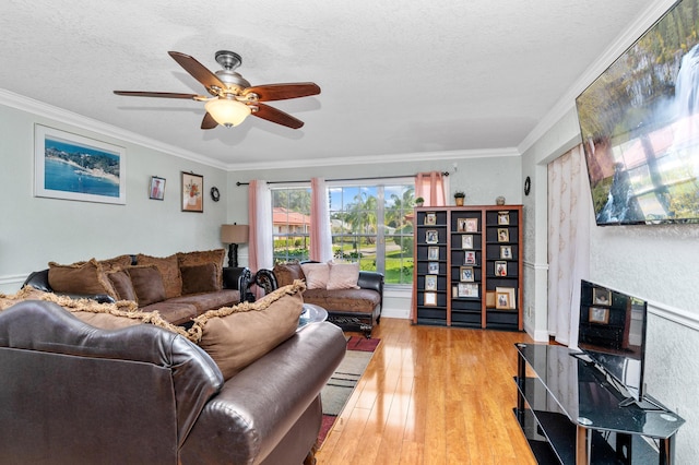 living room featuring light wood-style floors, a fireplace, ornamental molding, and a textured ceiling