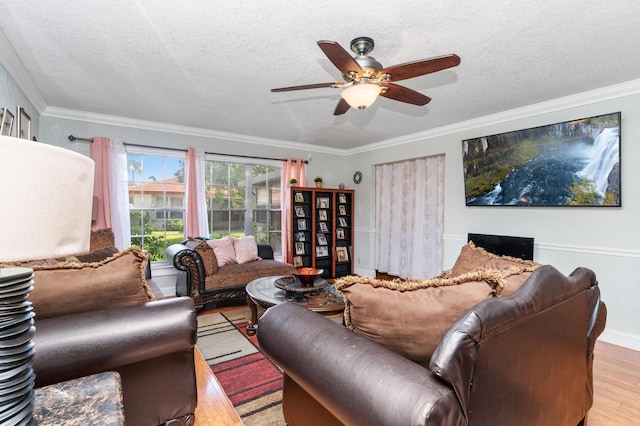 living room with light wood-style floors, ceiling fan, a textured ceiling, and crown molding