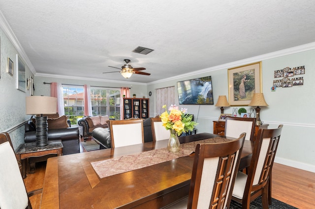 dining space with visible vents, wood finished floors, and ornamental molding