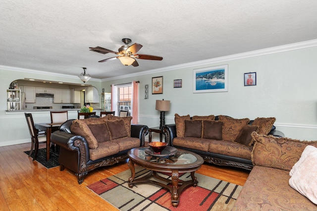 living room with ornamental molding, light wood-type flooring, and ceiling fan