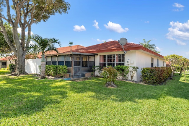 rear view of property featuring a yard, fence, and stucco siding