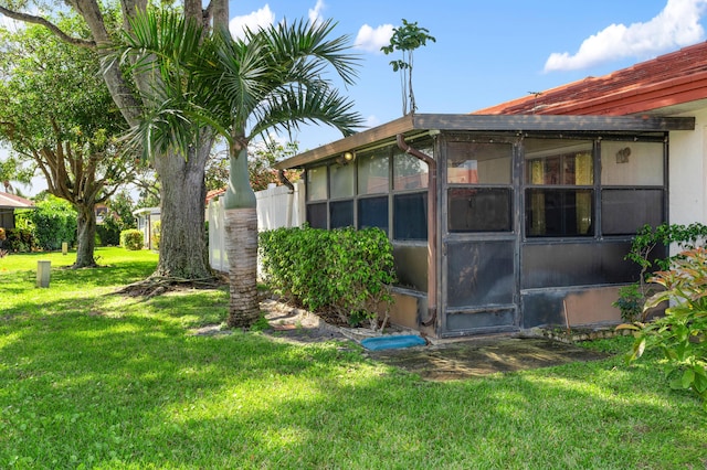 view of side of home with a lawn and a sunroom