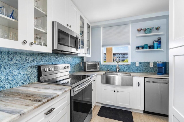 kitchen with stainless steel appliances, a sink, and white cabinetry